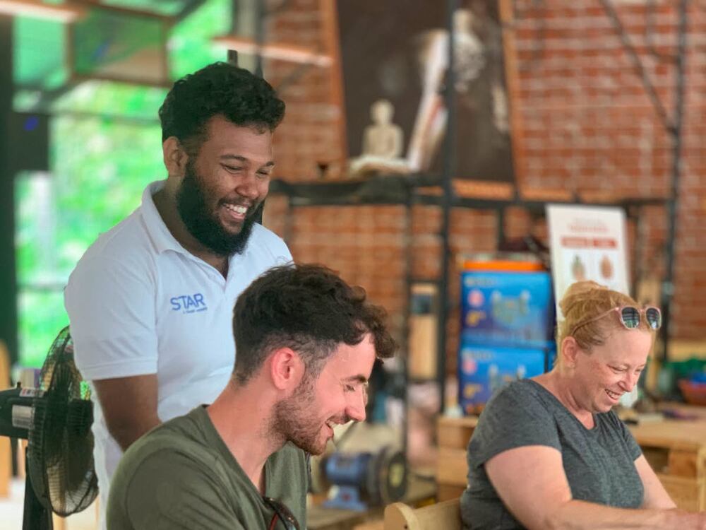 Visitors laughing together on the bench at the Impact Center studio in Sigiriya.