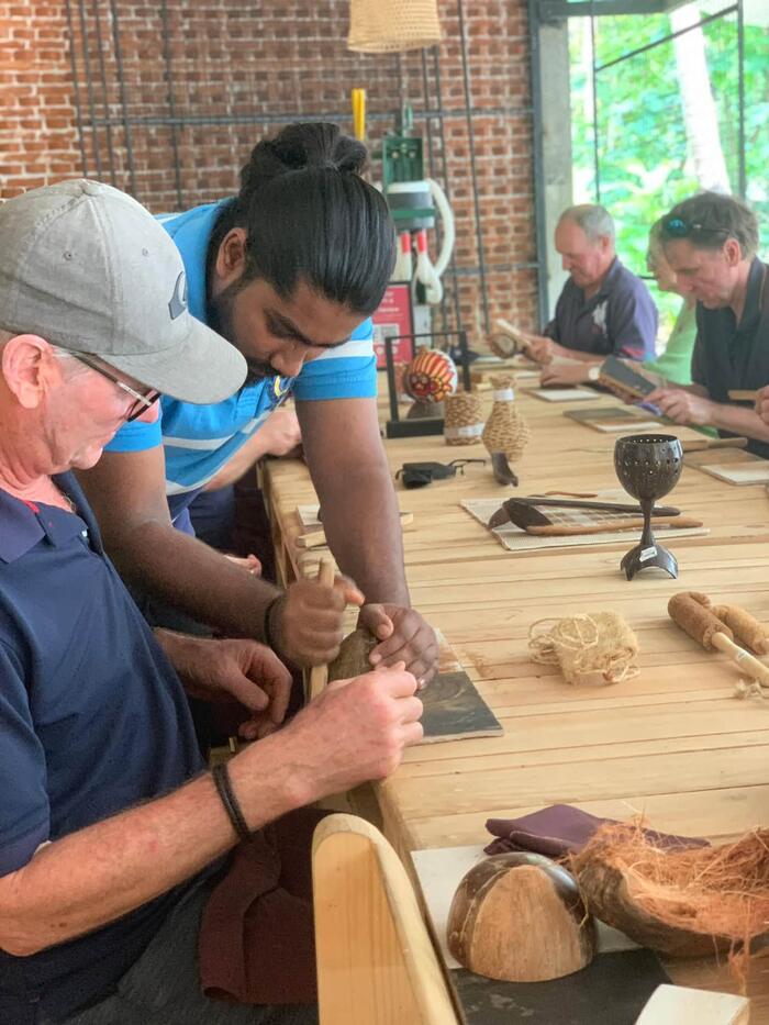 An artisan guiding a visitor's hands while carving, part of the Tree of Life experience in Sigiriya.