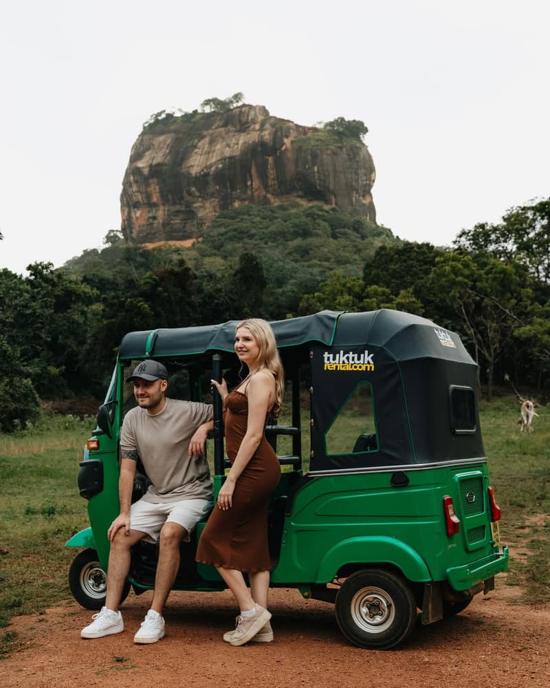 A couple standing beside their hired tuk-tuk on a track below Sigiriya Lion Rock.