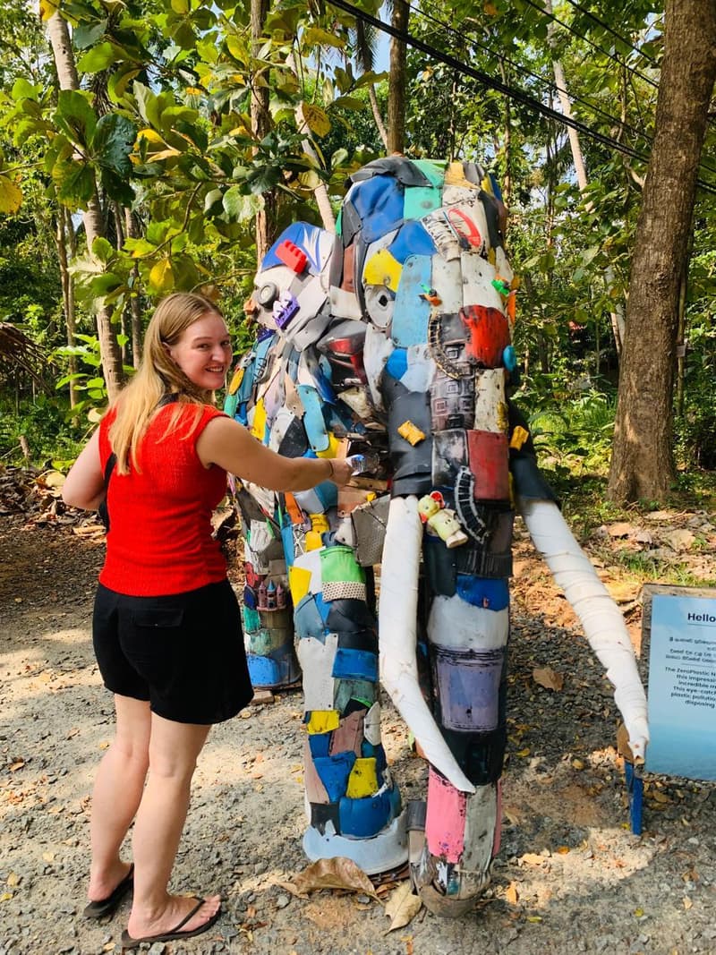 A traveller placing a plastic bottle into the ZeroPlastic Elephant, a life-size sculpture built from salvaged plastic beside the road in Sigiriya.