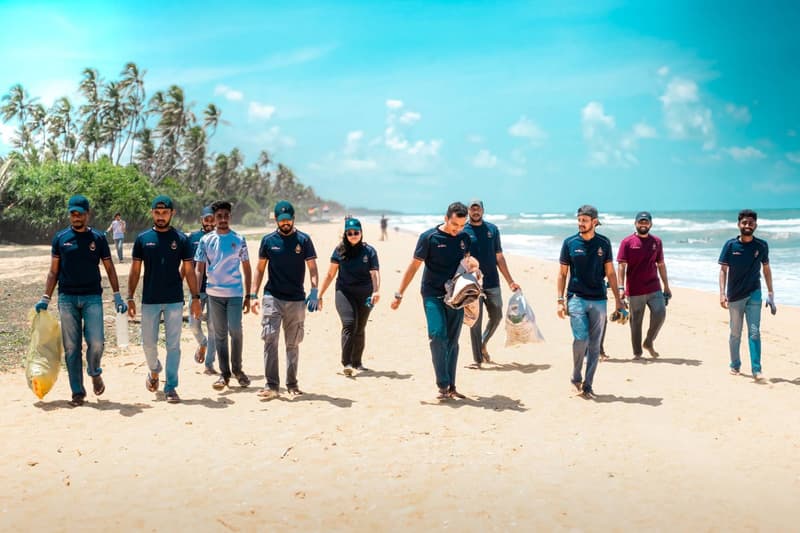 ZeroPlastic volunteers walking along a Sri Lankan beach carrying bags of collected waste.